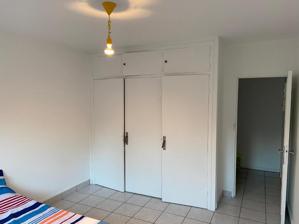 a bedroom with a white cabinet and a bed at Bel appartement spacieux, lumineux avec parking in Ris-Orangis