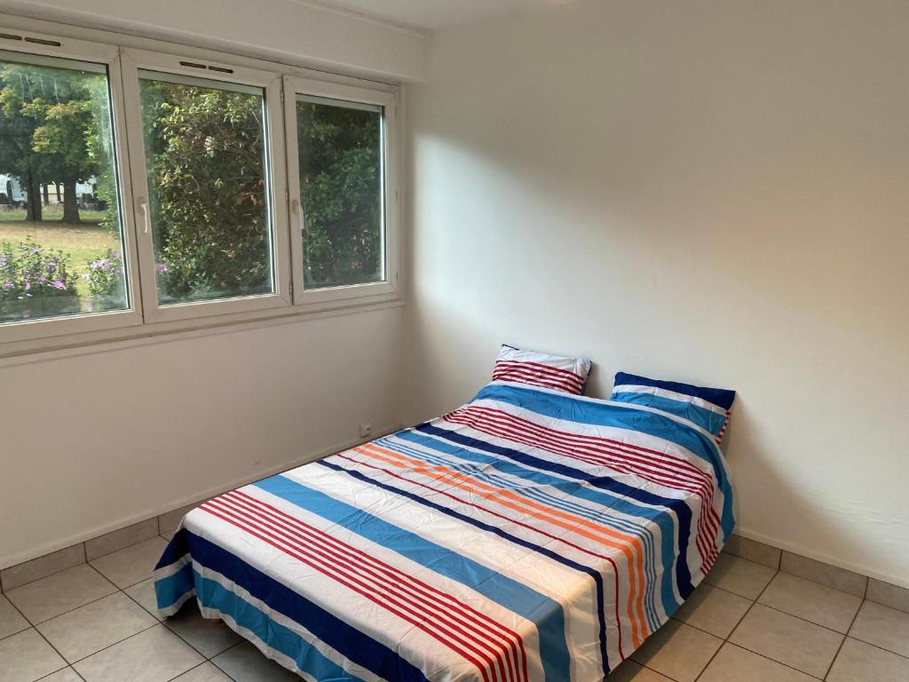 a bed sitting in a room with two windows at Bel appartement spacieux, lumineux avec parking in Ris-Orangis