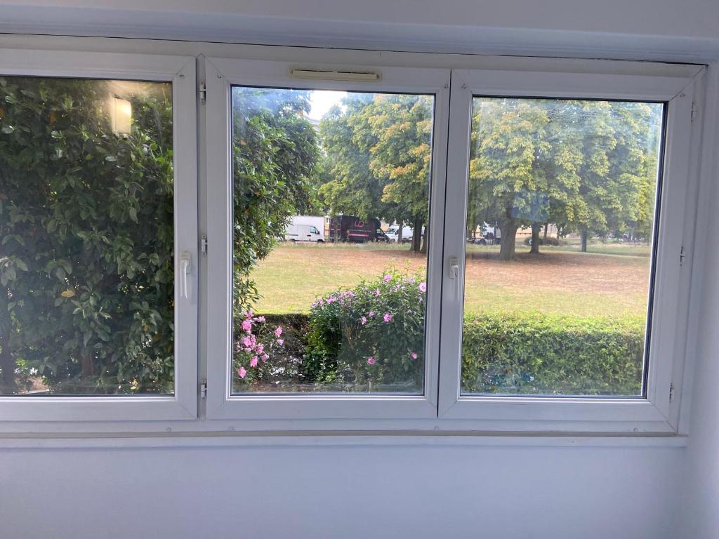 a window with a view of a park through it at Bel appartement spacieux, lumineux avec parking in Ris-Orangis