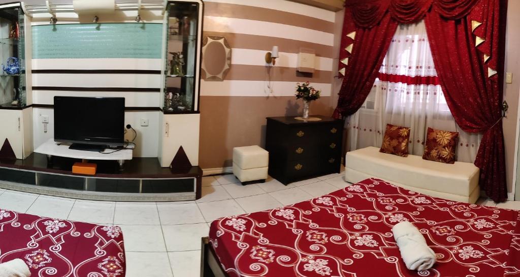 a bedroom with a bed and a television in it at Center Parkway Pension House in Kalibo