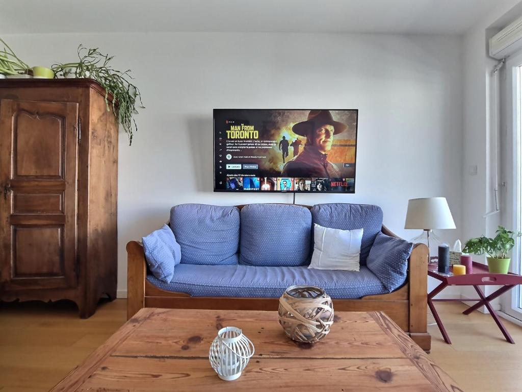 uma sala de estar com um sofá azul e uma mesa em Au cœur d'Agroparc em Avignon
