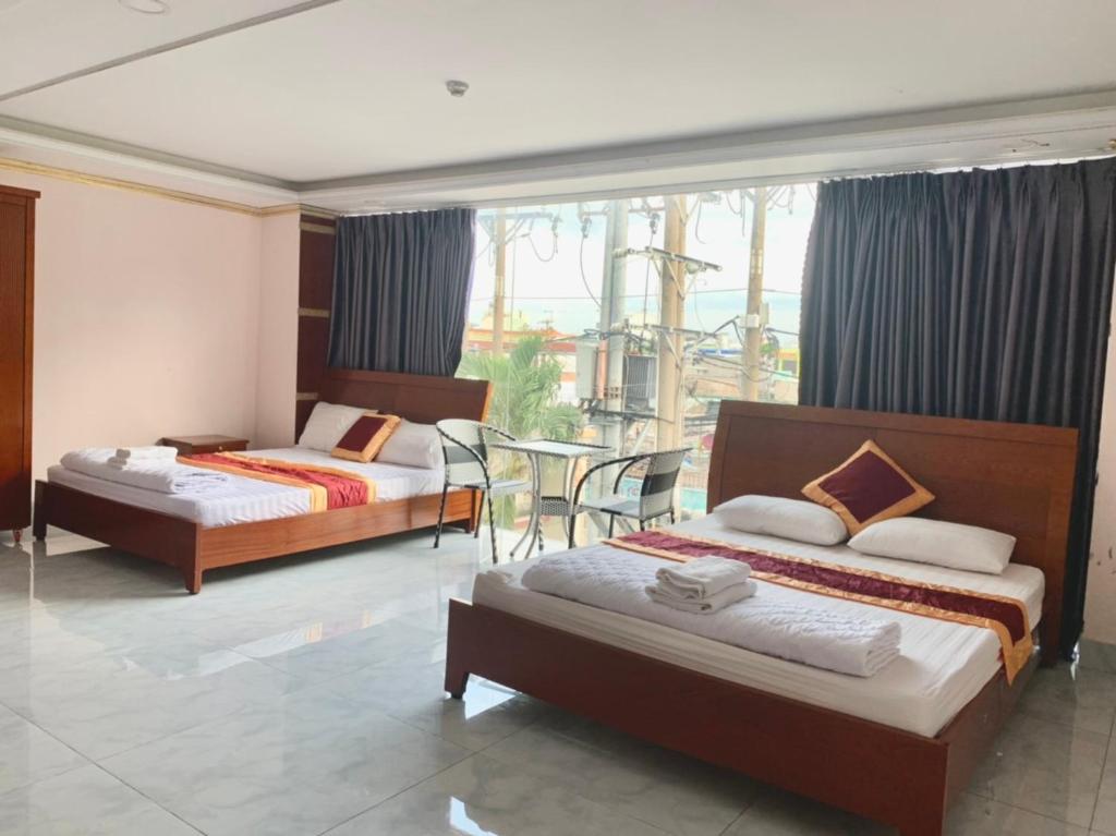 OYO 1170 Nhan Duc Hotel في مدينة هوشي منه: غرفة نوم بسريرين وطاولة ونافذة
