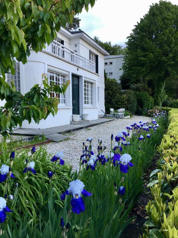 a garden with blue flowers in front of a white house at Villa Millepertuis Bagnoles de l'Orne in Bagnoles de l'Orne