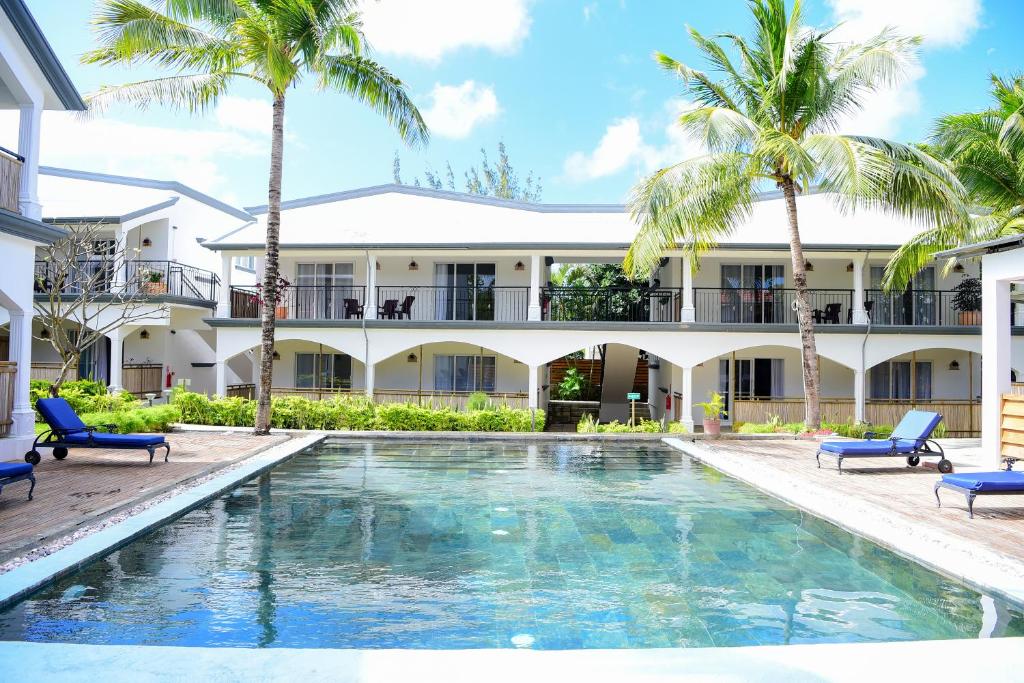 a swimming pool in front of a building with palm trees at Maison Du Nord in Pointe aux Canonniers