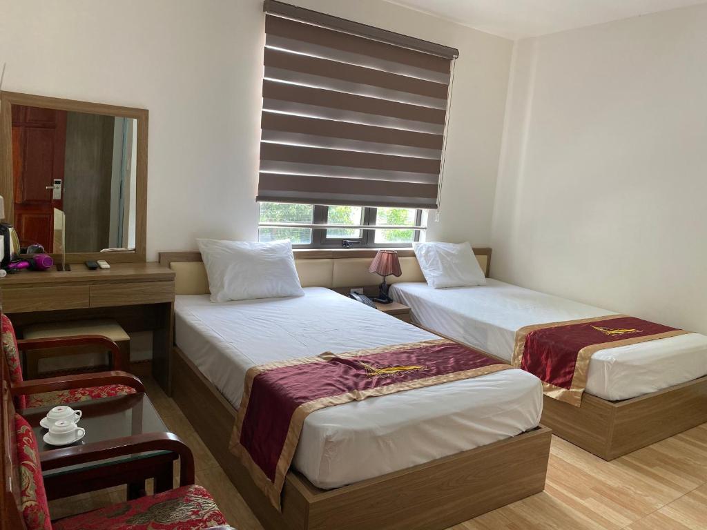 a hotel room with two beds and a window at Kim Ngan Ha Long Hotel in Ha Long