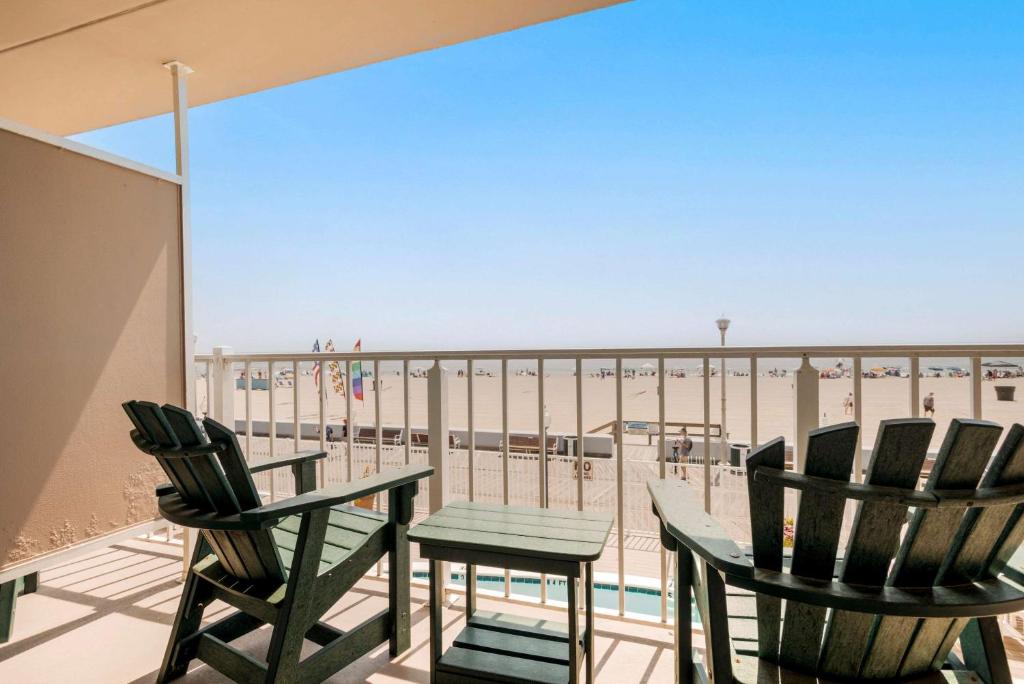 two chairs and a table on a balcony with the beach at Comfort Inn Ocean City Boardwalk in Ocean City