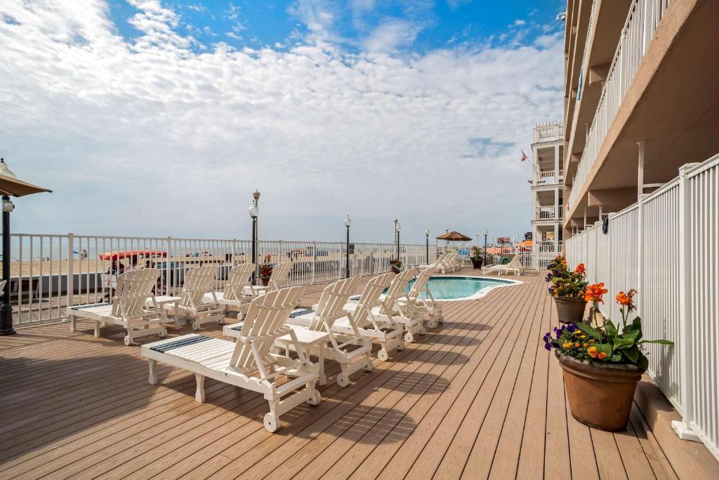 a deck with chairs and a swimming pool on the beach at Comfort Inn Ocean City Boardwalk in Ocean City