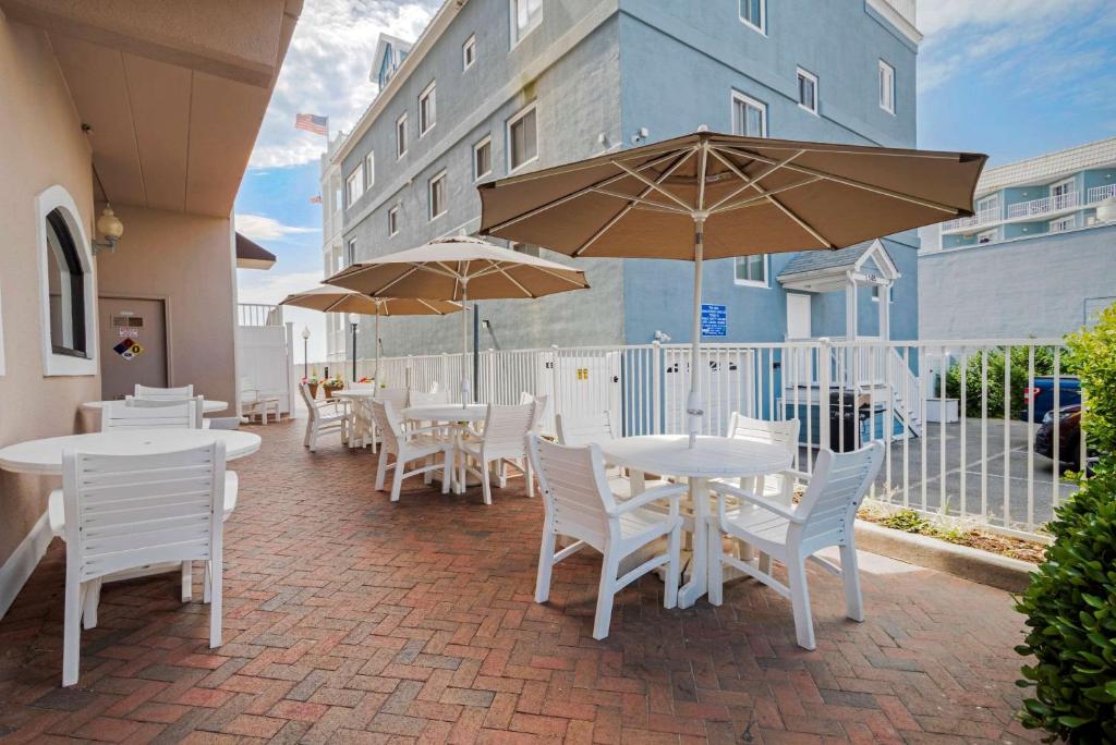 a patio with white tables and chairs and umbrellas at Comfort Inn Ocean City Boardwalk in Ocean City