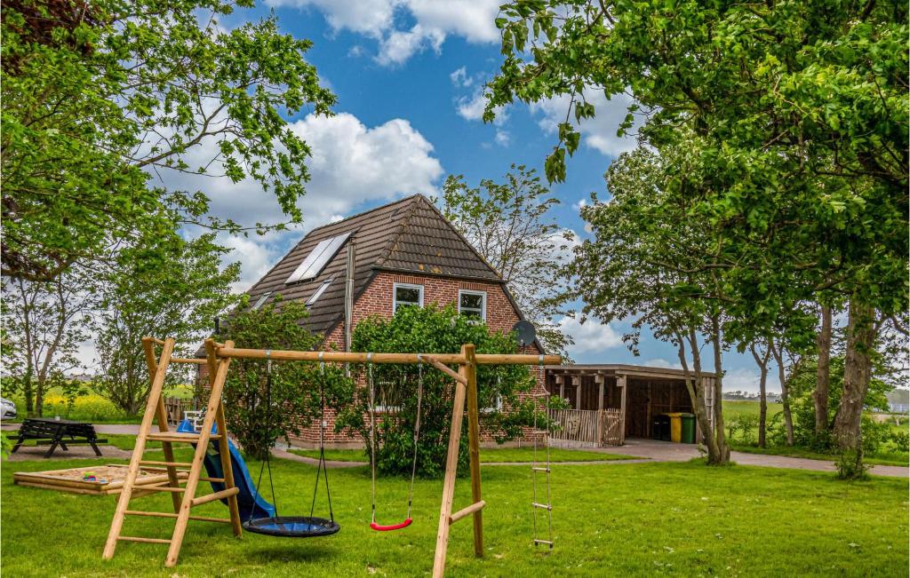 um parque infantil com um baloiço e uma casa em Nice Home In Niebll With Kitchen em Niebüll