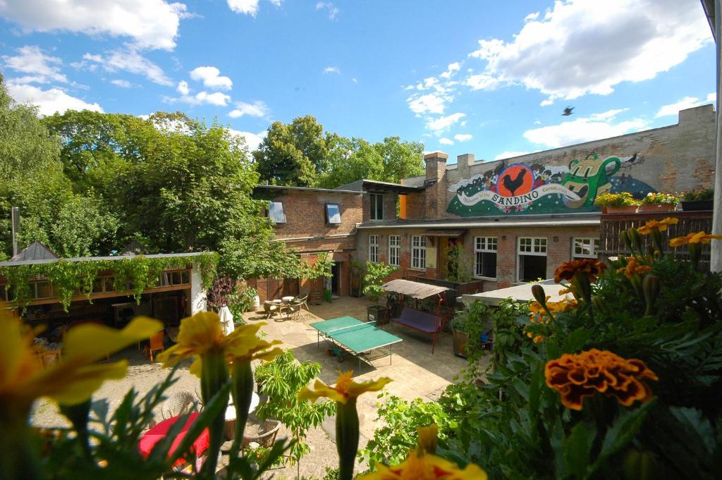ein Gebäude mit einem Garten mit Blumen und einer Terrasse in der Unterkunft Sandino Hostel - Solo Traveler Sanctuary in Berlin