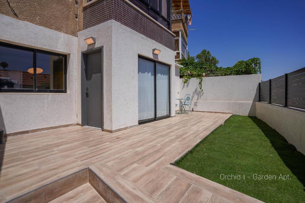 a garden with a wooden deck in front of a building at YalaRent Orchid Boutique Apartments in Eilat