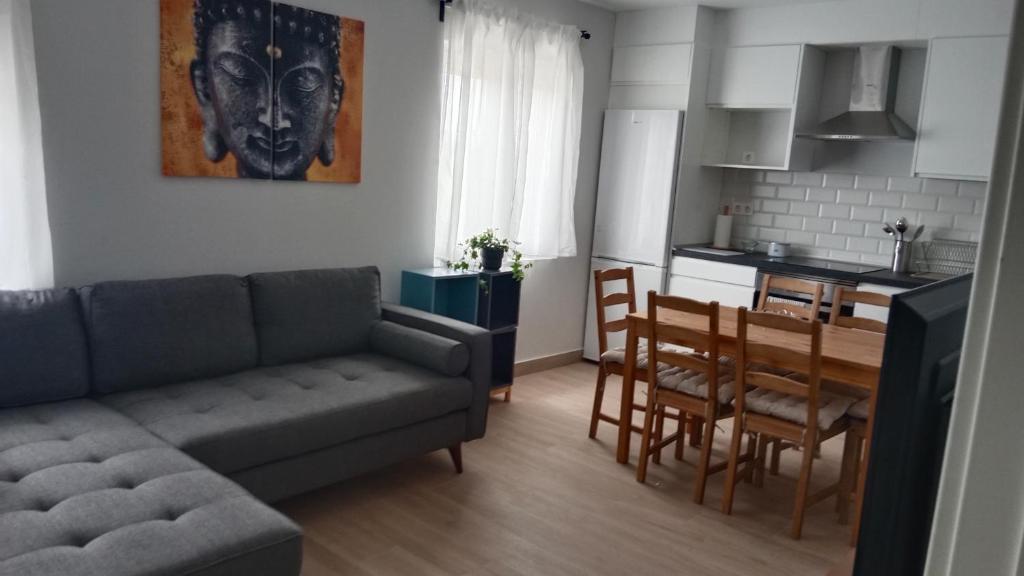 a living room with a couch and a table and a kitchen at Apartamento nuevo cerca de la costa y a 15 min de Bilbao! in Urduliz