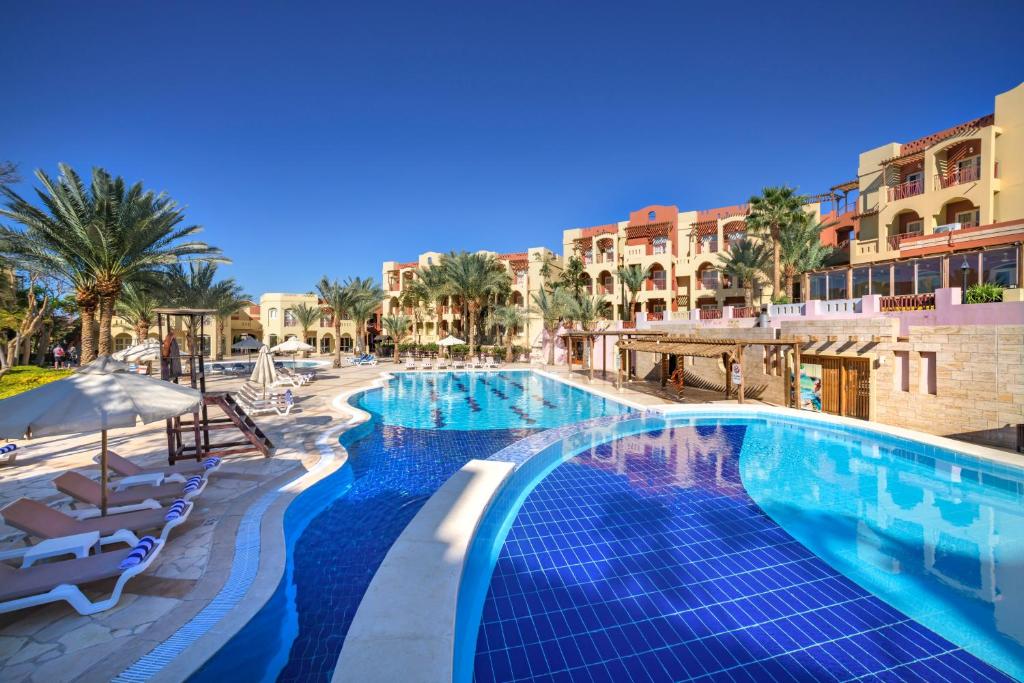 a pool at a resort with palm trees and buildings at Marina Plaza Hotel Tala Bay in Aqaba