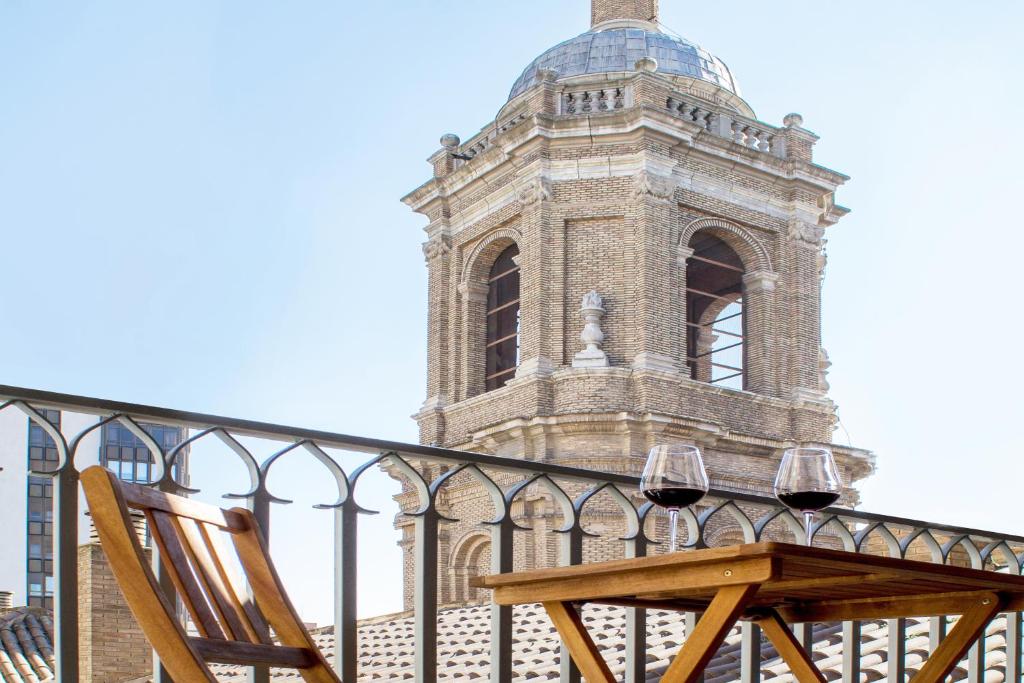 uma cadeira de madeira sentada em frente a um edifício com uma torre em Apartamento con vistas en centro histórico em Zaragoza