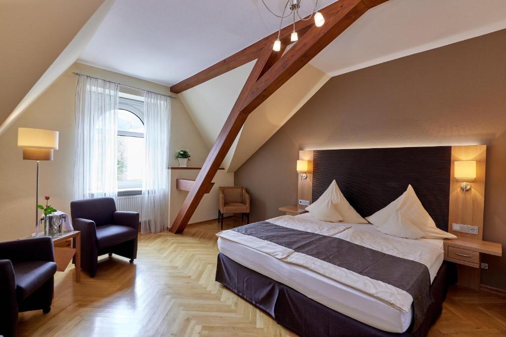 a bedroom with a large bed and a staircase at Hotel Sankt Maximilian in Bernkastel-Kues
