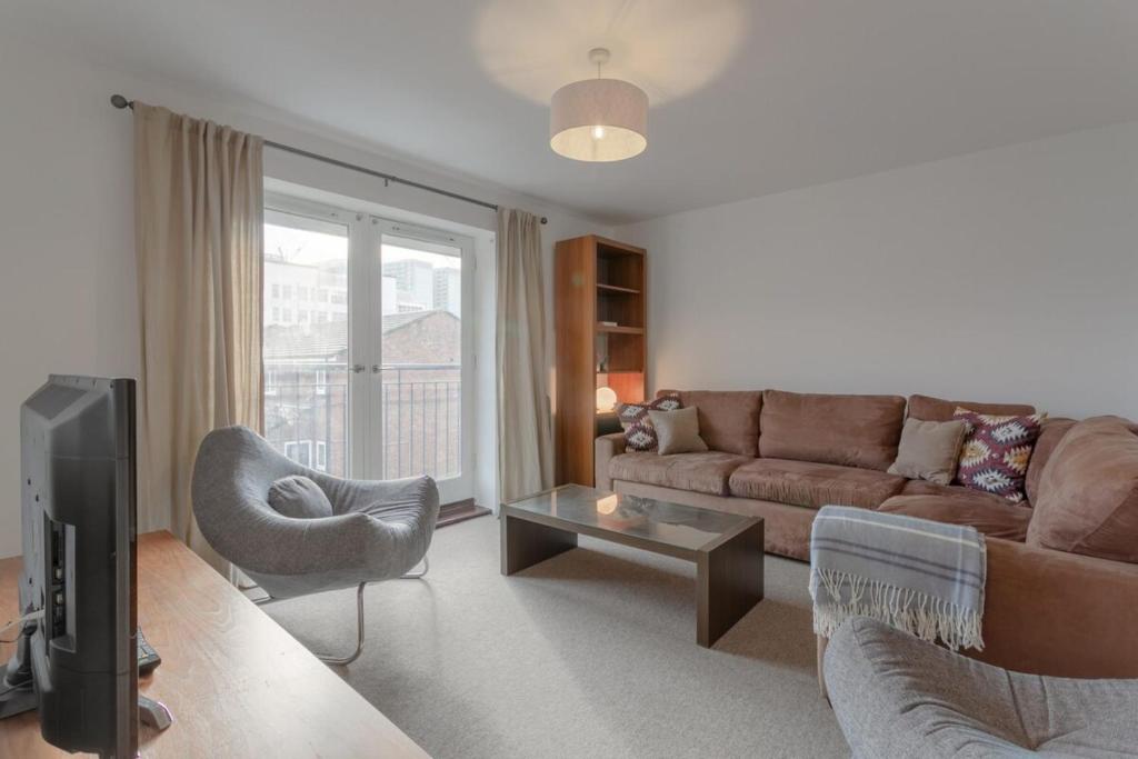 a living room with a couch and a chair at A Spacious 2 Bedroom Apartment In Aldgate East in London