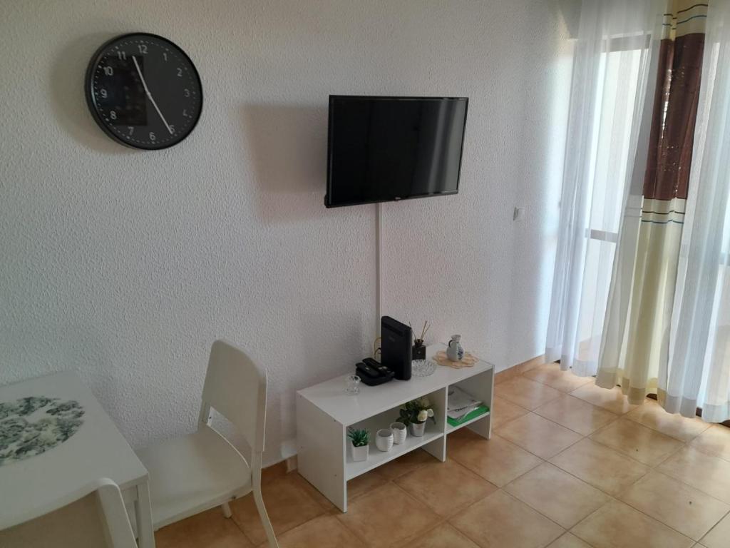 ein Wohnzimmer mit einem Tisch und einer Uhr an der Wand in der Unterkunft Apartamento Maria do Céu Villa Magna in Albufeira