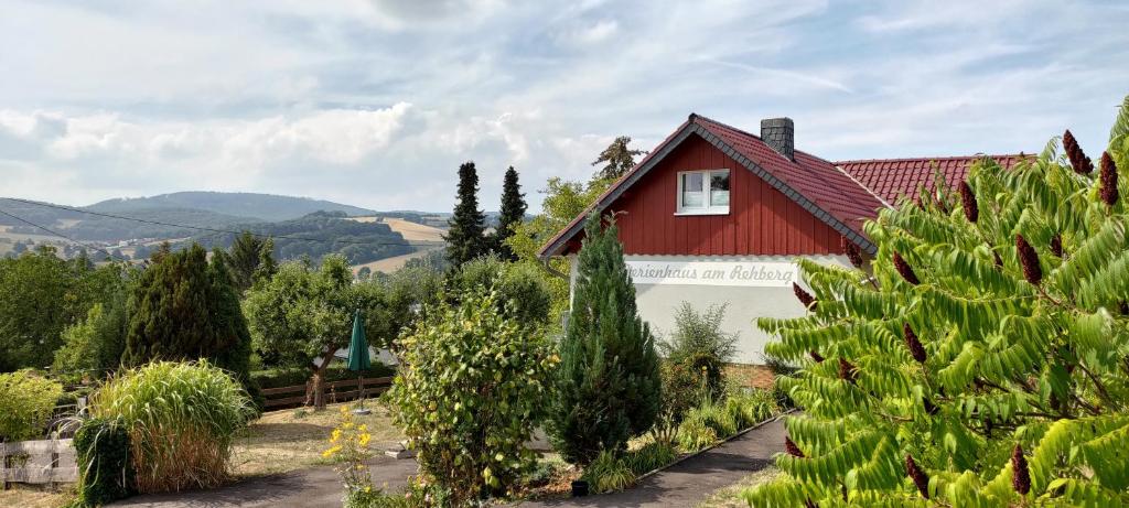 ein rotes Haus mit rotem Dach und einigen Bäumen in der Unterkunft Ferienhaus am Rehberg in Eisenach