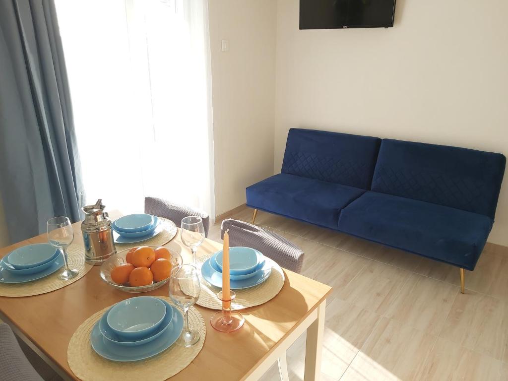 een woonkamer met een tafel en een blauwe bank bij Apartman Helena in Gradac