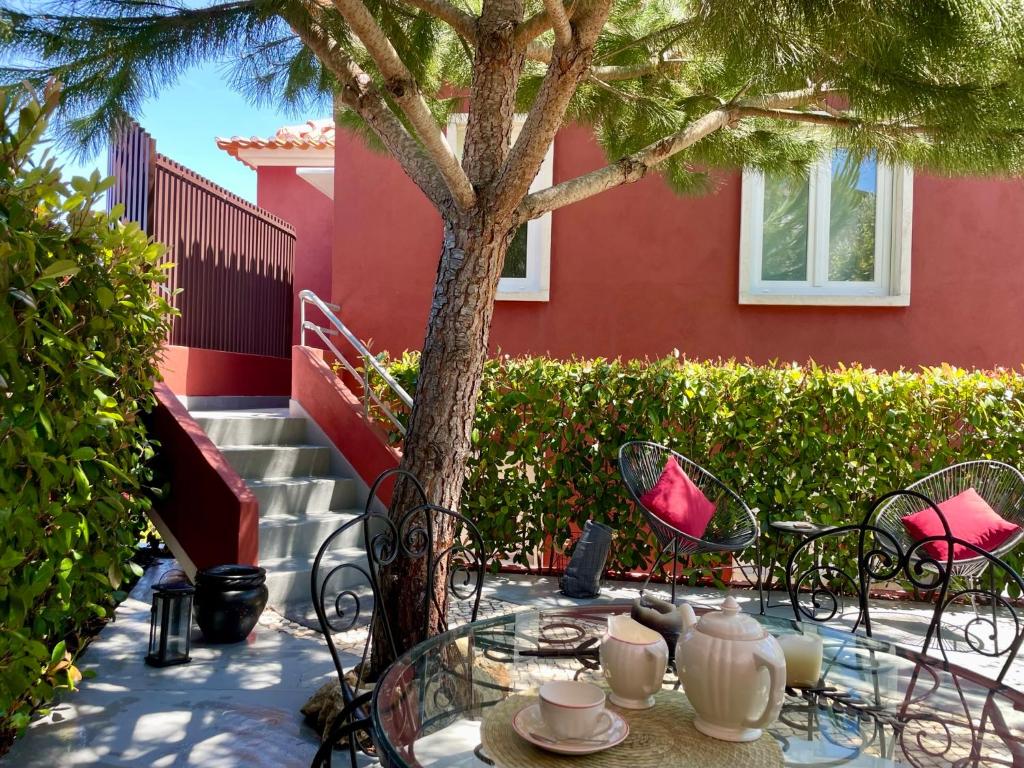 a table and chairs under a tree next to a building at Confluentia H&A - Believe It or Not Apartments in Coimbra