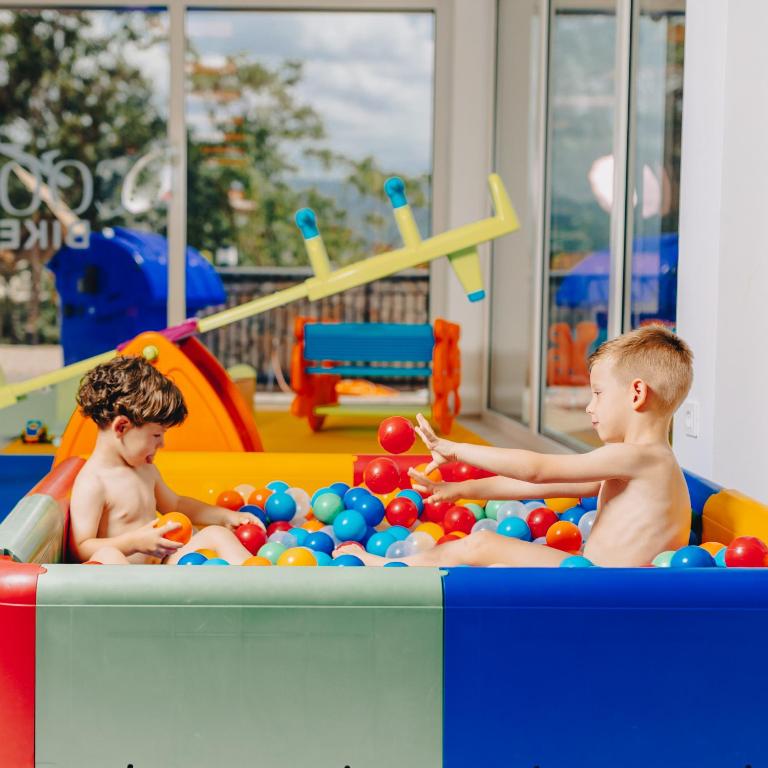 two young boys playing in a pool with balls at Cool Šilo Appartement Resort in Šilo