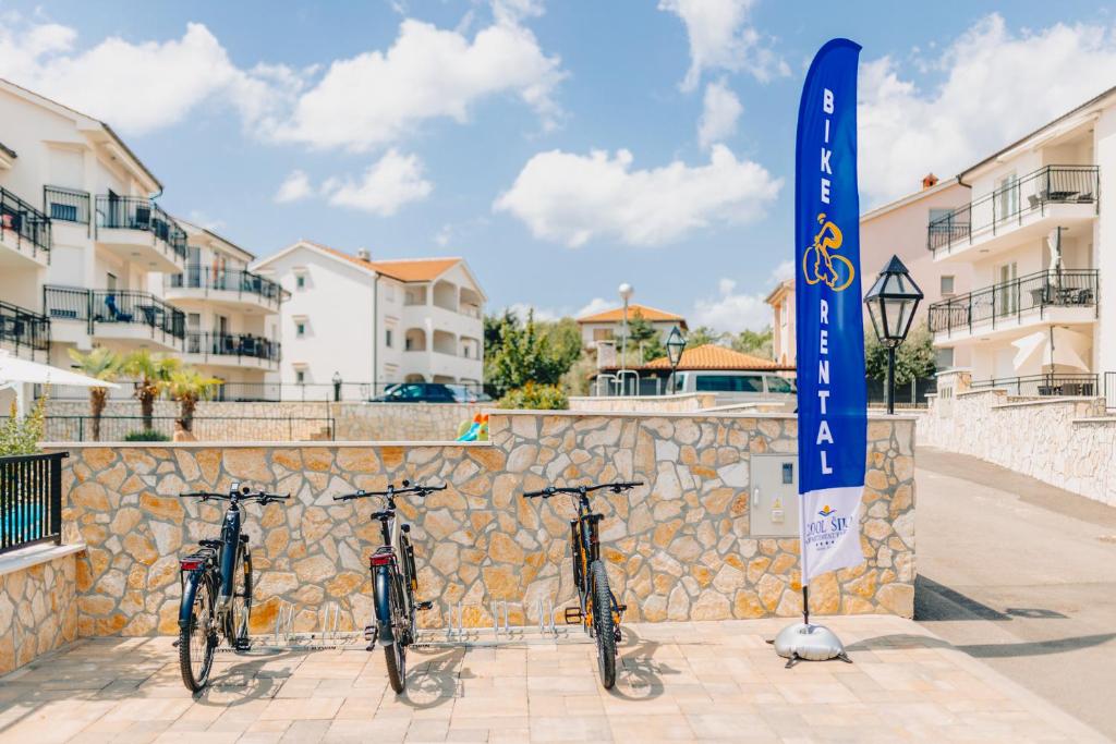 a group of bikes parked next to a stone wall at Cool Šilo Appartement Resort in Šilo