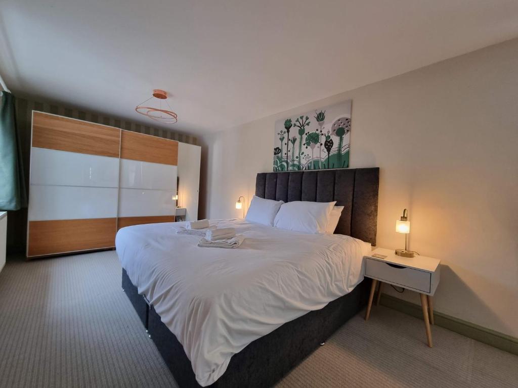 1 dormitorio con 1 cama blanca grande y mesita de noche en Kingsfield House by Cliftonvalley Apartments en Bristol