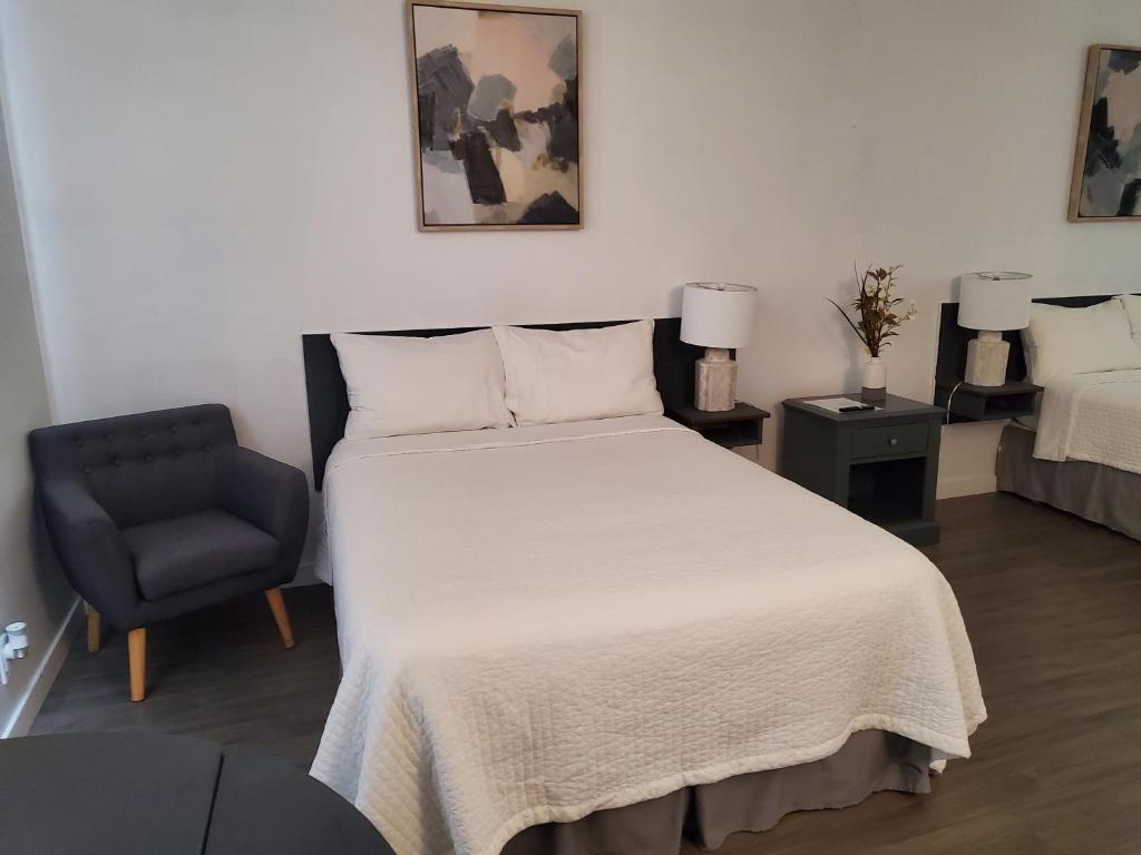 um quarto com uma cama branca e uma cadeira azul em Westview Motel em Raymore