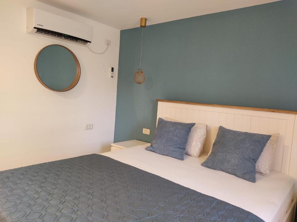 a bedroom with a bed with blue pillows and a mirror at רוגע במדבר מרחב עם in Merhav Am