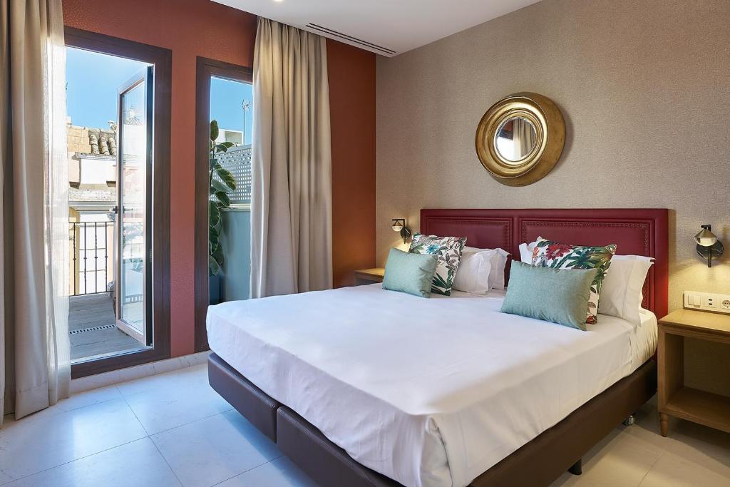 Un dormitorio con una cama grande y una ventana en Vincci Molviedro Suites Apartments, en Sevilla