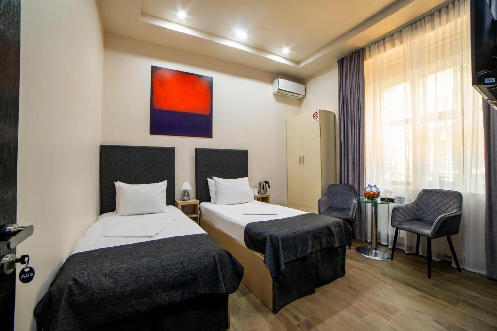 una habitación de hotel con 2 camas y una silla en Elysium Gallery Hotel, en Ereván
