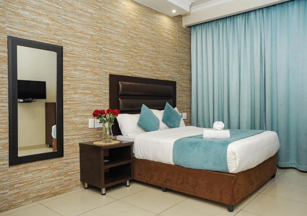 1 dormitorio con 1 cama grande y espejo en Bayside Hotel Pietermaritzburg, en Pietermaritzburg