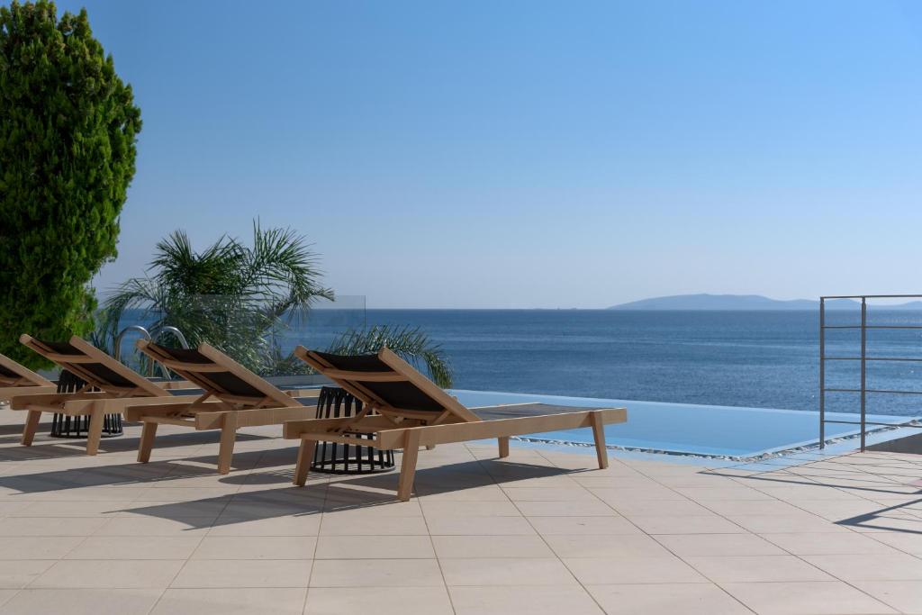 een rij houten ligstoelen naast een zwembad bij Anima SeaView Luxury Living Villa, By ThinkVilla in Gázion