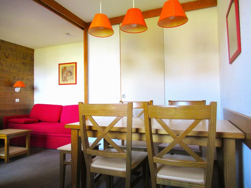 een eetkamer met een tafel en stoelen en een rode bank bij Appartement 644 au pied des pistes de Belle Plagne in La Plagne Tarentaise