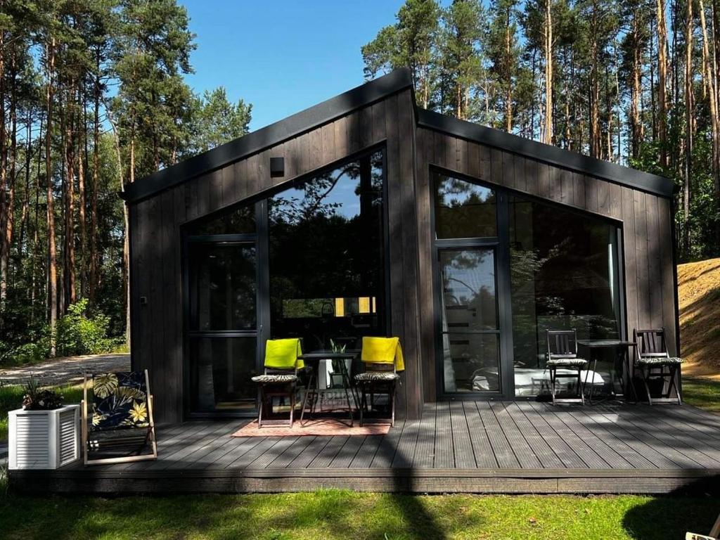 a modern house with glass doors and a deck at Brama do lasu - Domek Relaksu in Borków