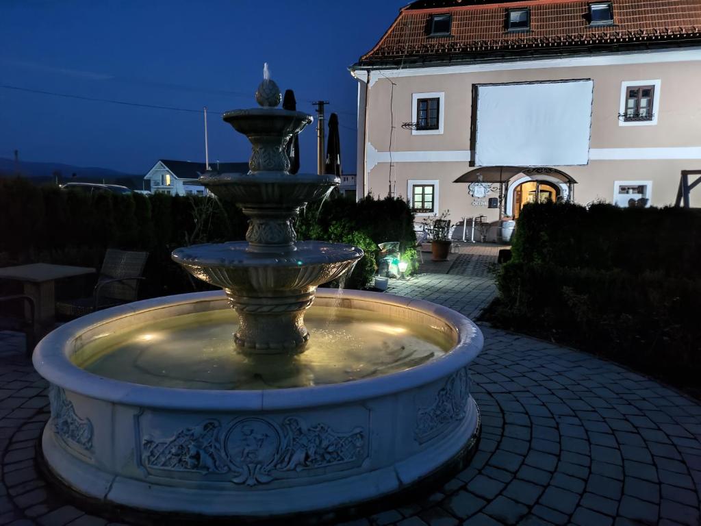 einen Brunnen vor einem Haus in der Nacht in der Unterkunft Kaštieľ Ottlýk in Bánovce nad Bebravou