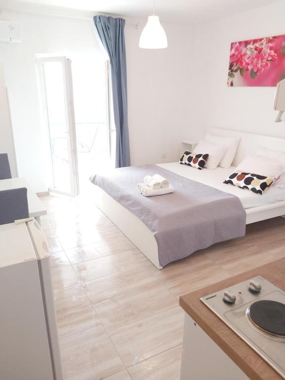 ein weißes Schlafzimmer mit einem großen Bett und einer Küche in der Unterkunft Studio apartman Marley in Gradac