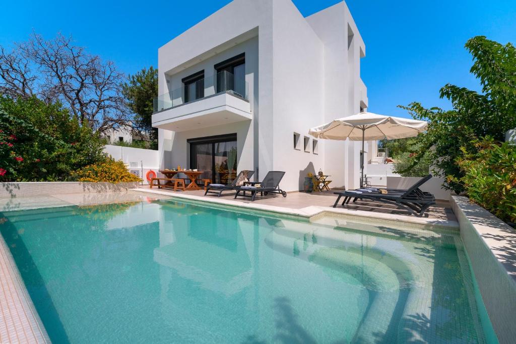 a villa with a swimming pool in front of a house at Thalassa Luxury Villa in Ialyssos