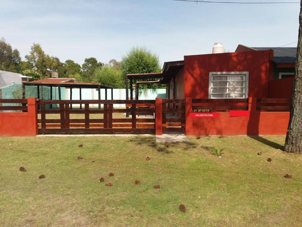 una casa roja con una valla y un árbol en Casas del Mar en San Bernardo