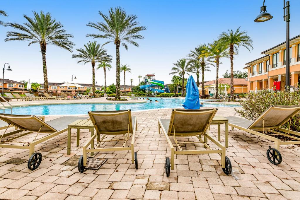 un grupo de sillas junto a una piscina con palmeras en Modern Retreat at Regal Oaks Resort, en Orlando