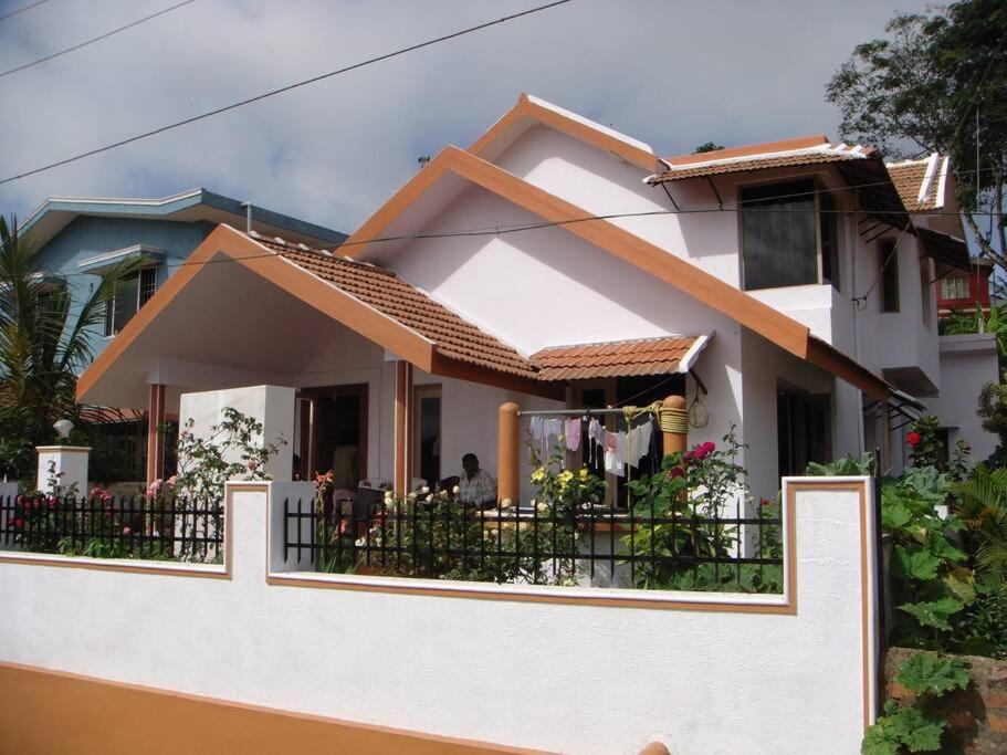 a white house with a balcony with a fence at La Paz Coorg homestay at Madikeri town in Madikeri