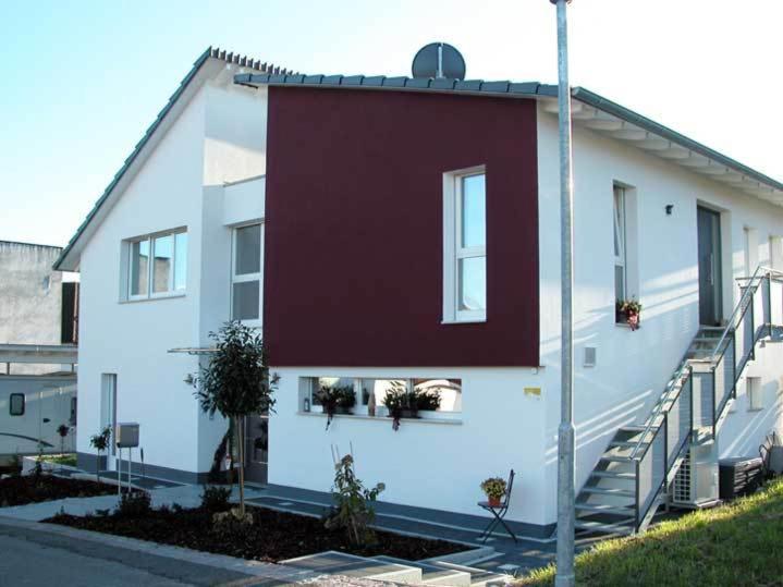 ein weißes Haus mit einer roten Wand an der Seite in der Unterkunft Ferienwohnung am Bienenfeld in Ettenheim