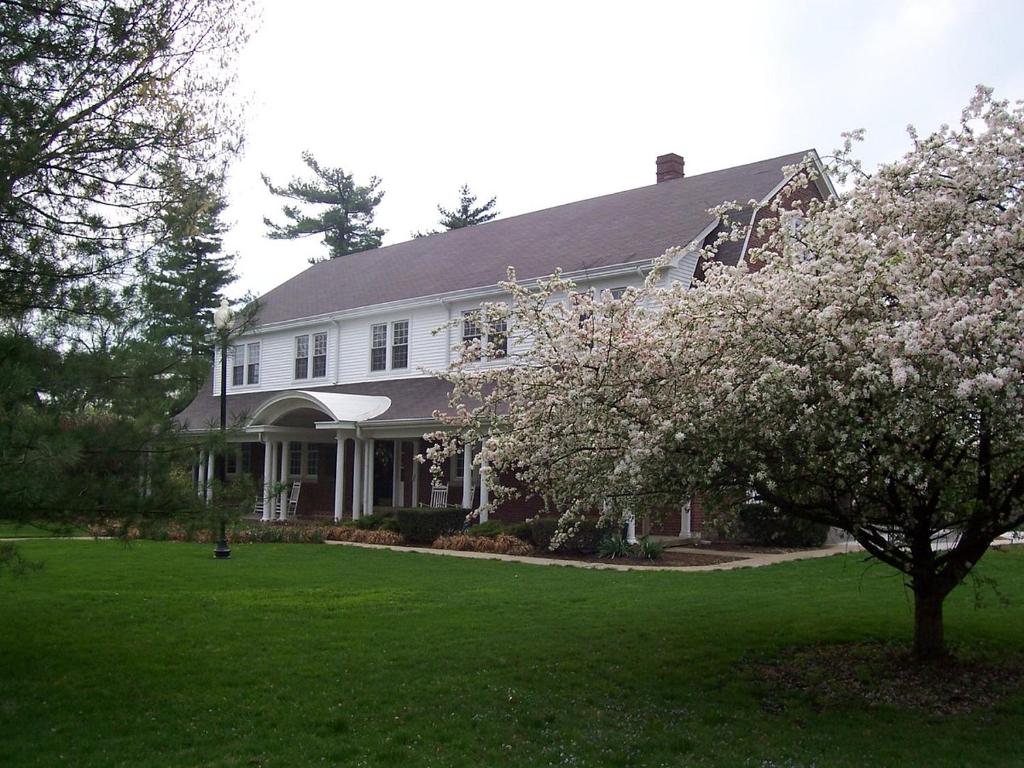 a white house with a flowering tree in the yard at The Woodford Inn in Versailles