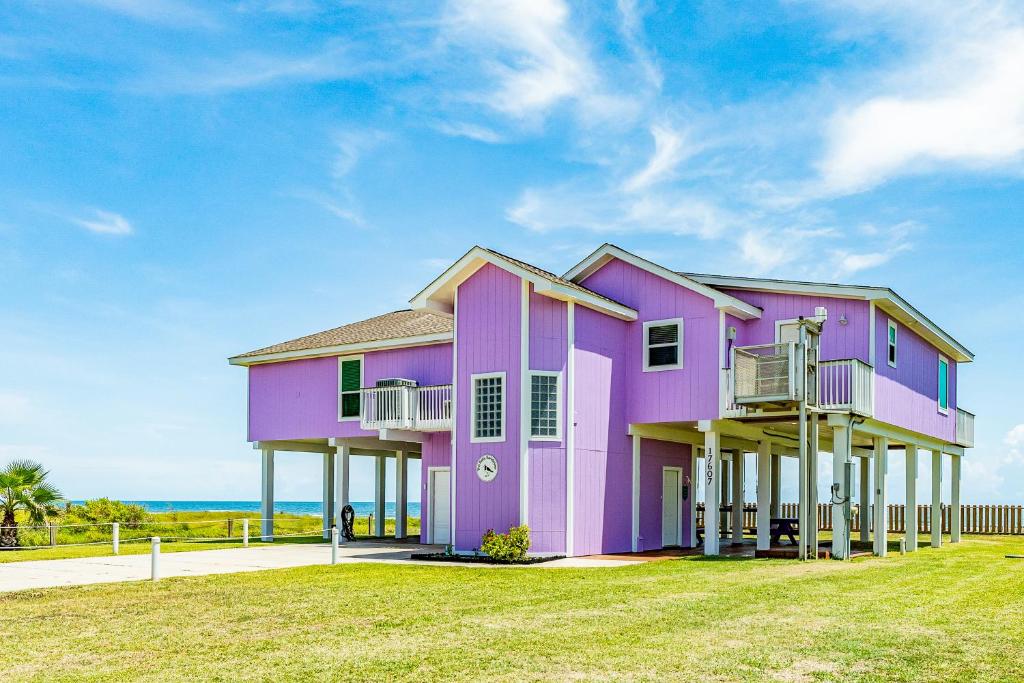 ein lila Haus mit dem Ozean im Hintergrund in der Unterkunft Salty Sandpiper in Galveston