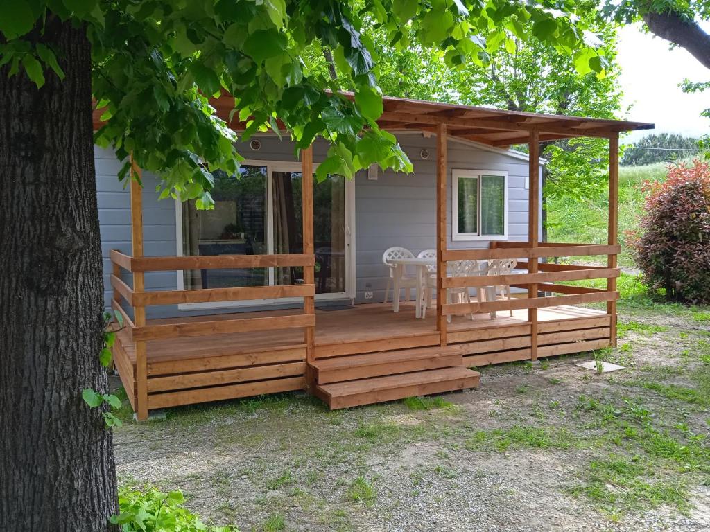 a cabin with a wooden deck next to a tree at Mobile home Ameglia - Including airco - Camping River- 328 in Ameglia
