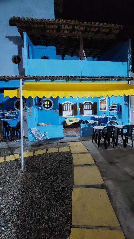 un edificio azul con toldo amarillo, mesas y sillas en PARAÍSO TOM DO MAR 2, en Arraial do Cabo