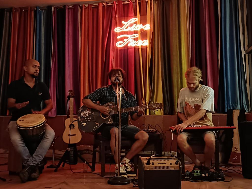 un groupe d'hommes assis dans une pièce à jouer aux instruments dans l'établissement Live Free Hostel Rishikesh, à Rishikesh