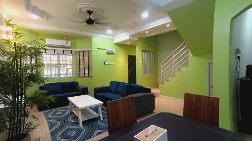 een woonkamer met groene muren en blauwe meubels bij HOMESTAY DR. Z (MUSLIM HOMESTAY) in Klang