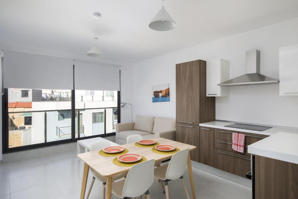- une cuisine et une salle à manger avec une table et des chaises dans l'établissement Cosy, Modern 1 Bedroom Apartment (Qawra), à San Pawl il-Baħar