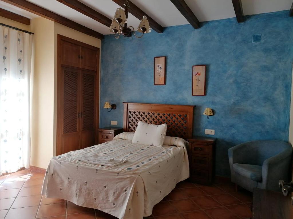 a bedroom with a bed and a blue wall at Casa rural Suerte de los Mozos in Cáceres